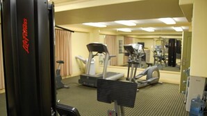 A gym with cardio machines, weight equipment, and a large mirror reflecting the space.