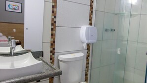 Un baño con lavabo, inodoro y cabina de ducha con mampara de vidrio.