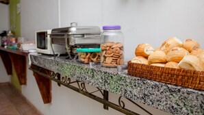 A buffet setup with a microwave, jars of cookies, and a basket of bread. - Pousada Sucuri (Bonito)