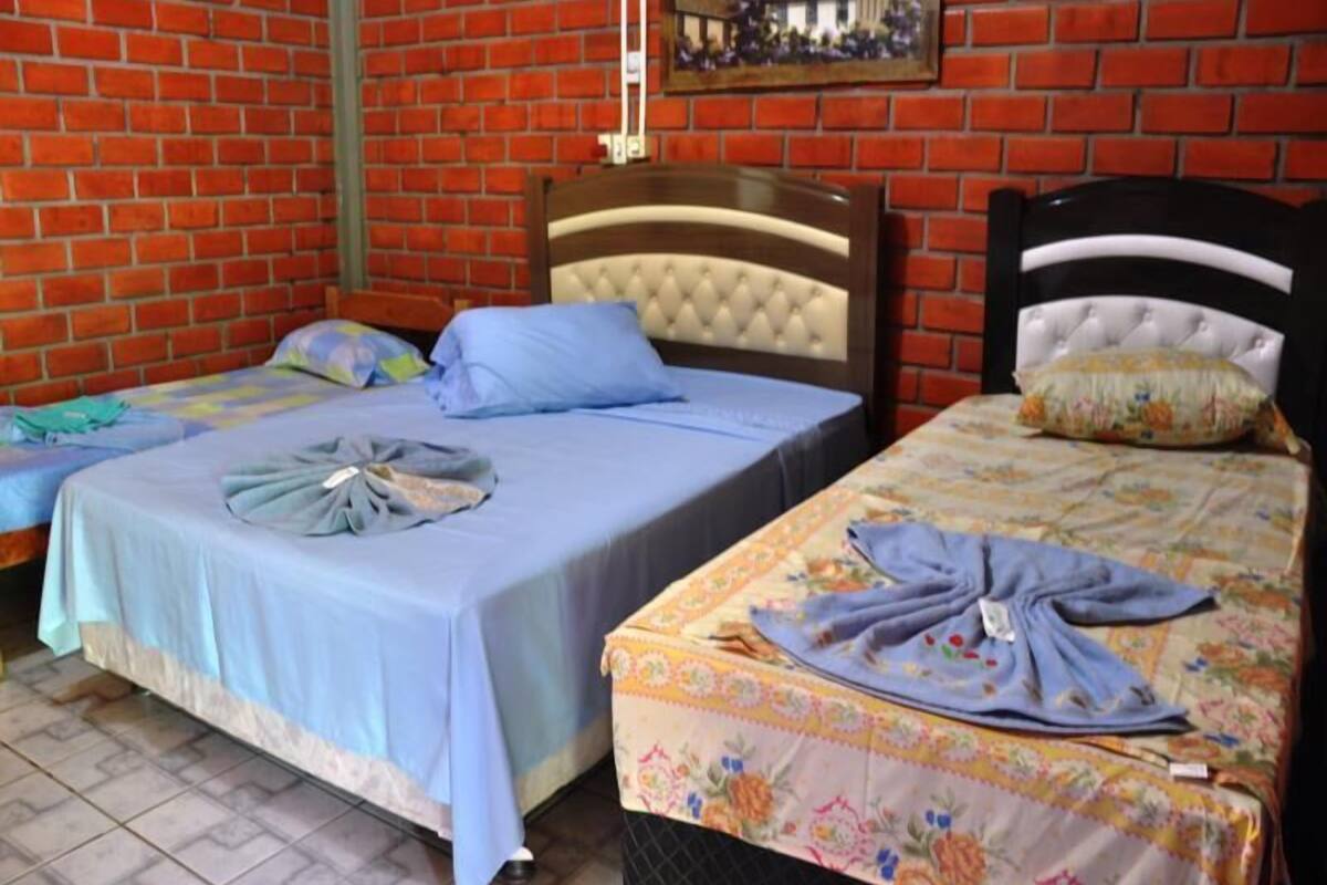 Quarto com duas camas, cada uma com cabeceira e colcha azul.