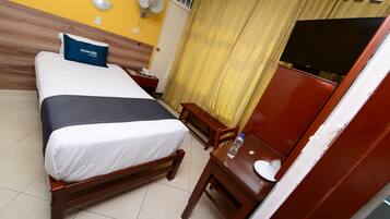 Habitación de hotel con cama, mesita de noche, silla, escritorio y televisor.