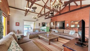A spacious living area with a high ceiling, wooden beams, a large sofa, a coffee table, and a television. -  HOTEL PARAÍSO DAS ÁGUAS BONITO (Bonito)