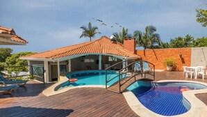A pool area with a wooden deck, a covered seating area, and a building with a tiled roof. -  HOTEL PARAÍSO DAS ÁGUAS BONITO (Bonito)