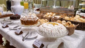 A buffet table with various desserts and bread baskets, including a peach cake and a chocolate cake. -  HOTEL PARAÍSO DAS ÁGUAS BONITO (Bonito)