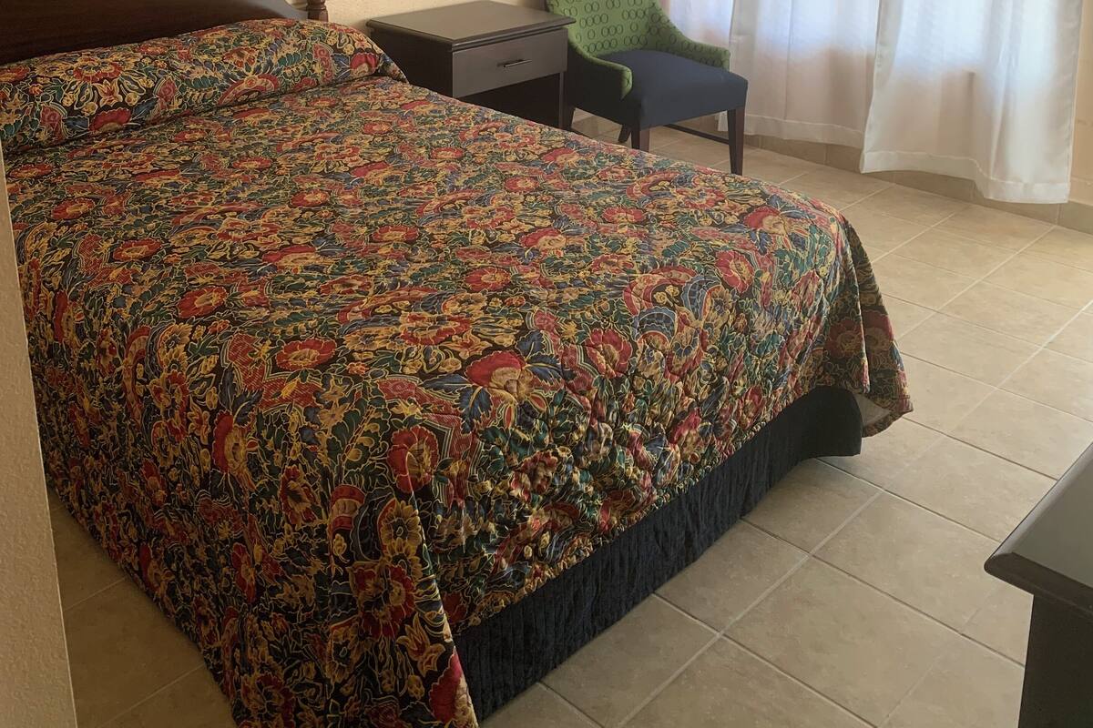 Una camera da letto con un letto grande, un comodino, una sedia e una finestra con tende.