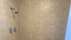 A small, tiled shower room with a showerhead and two faucets. - Loma Alta Motel (Laredo)