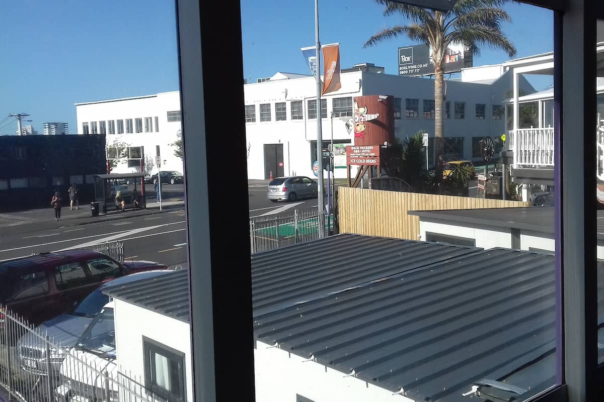 Vista de un edificio con un cartel que dice 'Box Living Co. NZ' y un cartel de 'Back Packers' que anuncia cervezas bien frías.