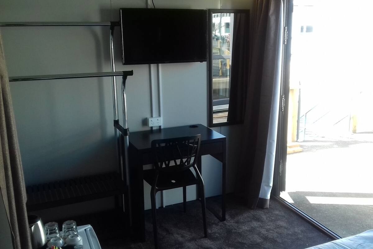 Una habitación de hotel con escritorio, silla y televisor montado en la pared.