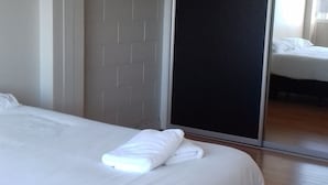 A modern hotel room with a large bed, a sliding door closet, and a wooden floor. - Shooters Saloon Bar Hotel & Cabins (Auckland)