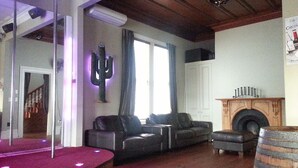 A living room with a wooden ceiling, a fireplace, a cactus decoration, and a red carpet. - Shooters Saloon Bar Hotel & Cabins (Auckland)