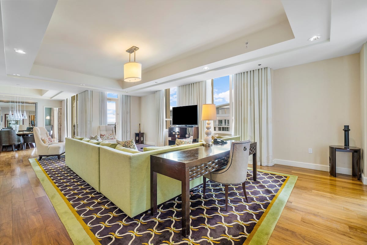 Amplia habitación de hotel con un sofá grande, una mesa de comedor, un televisor y un escritorio.