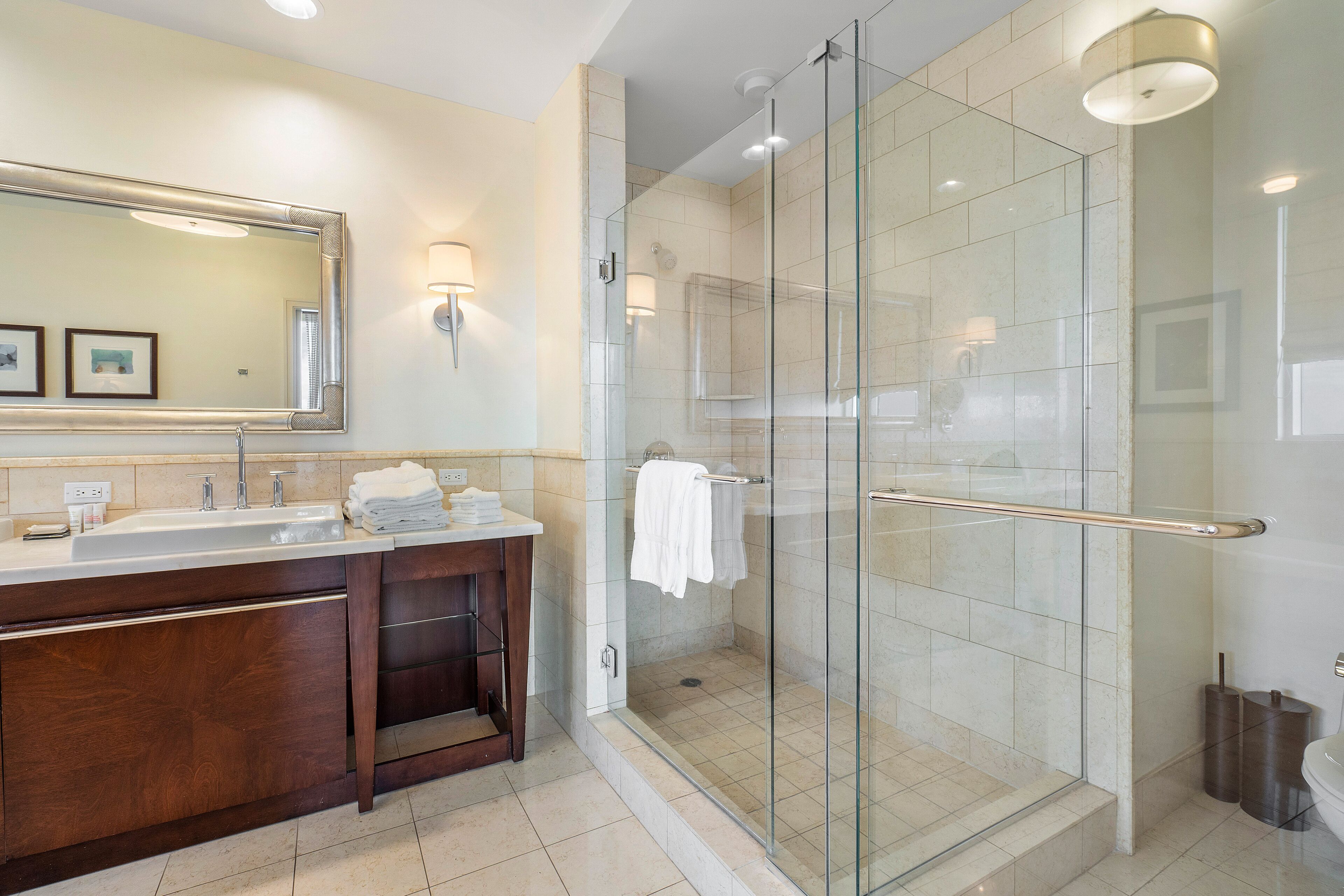 A modern bathroom with a glass-enclosed shower, a large mirror, and a vanity with a sink and towel rack.