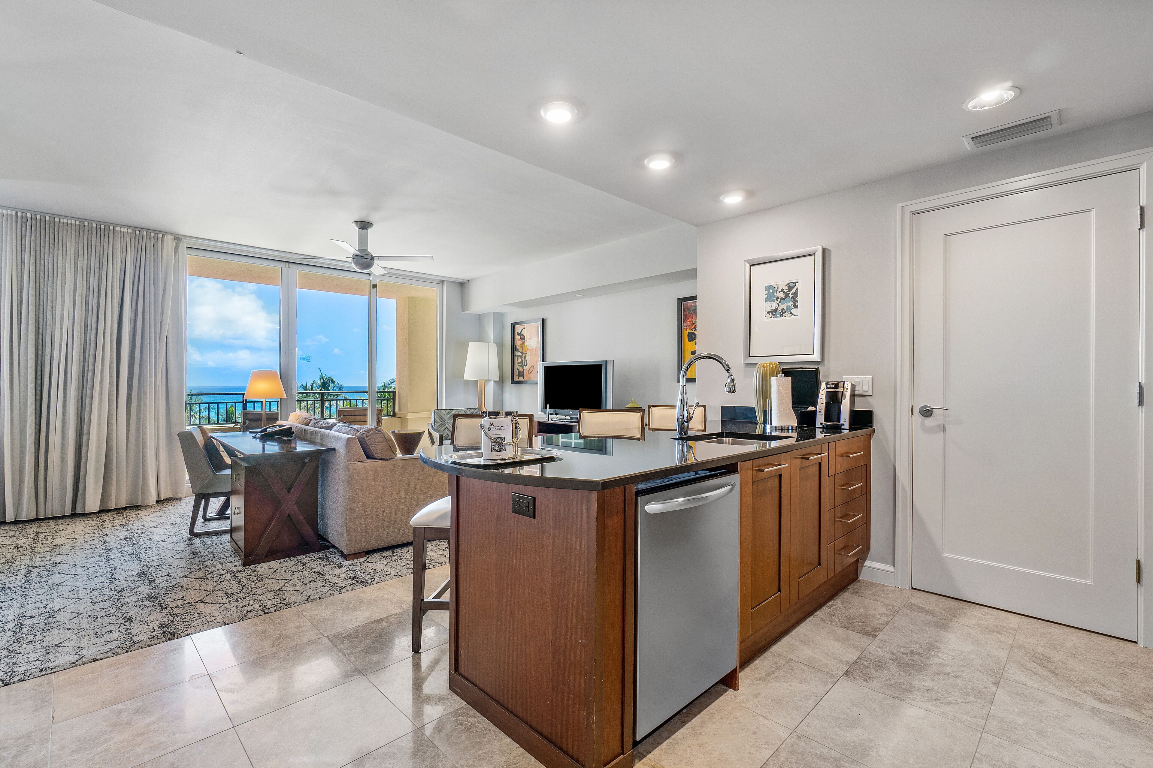 A modern kitchen with a central island, built-in appliances, and a dining area with a view.