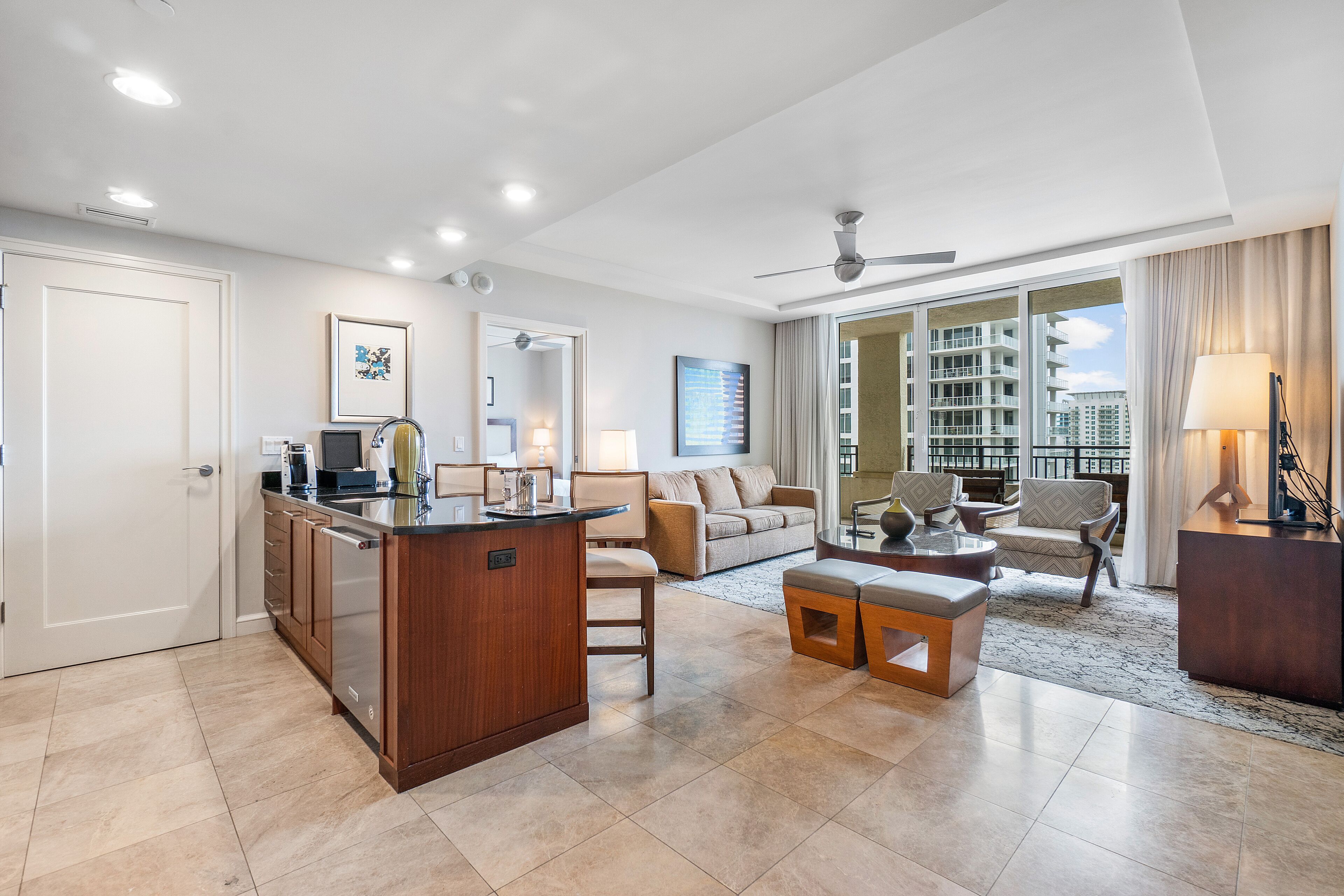 A modern living room with a kitchen area, a dining table, and a sofa.