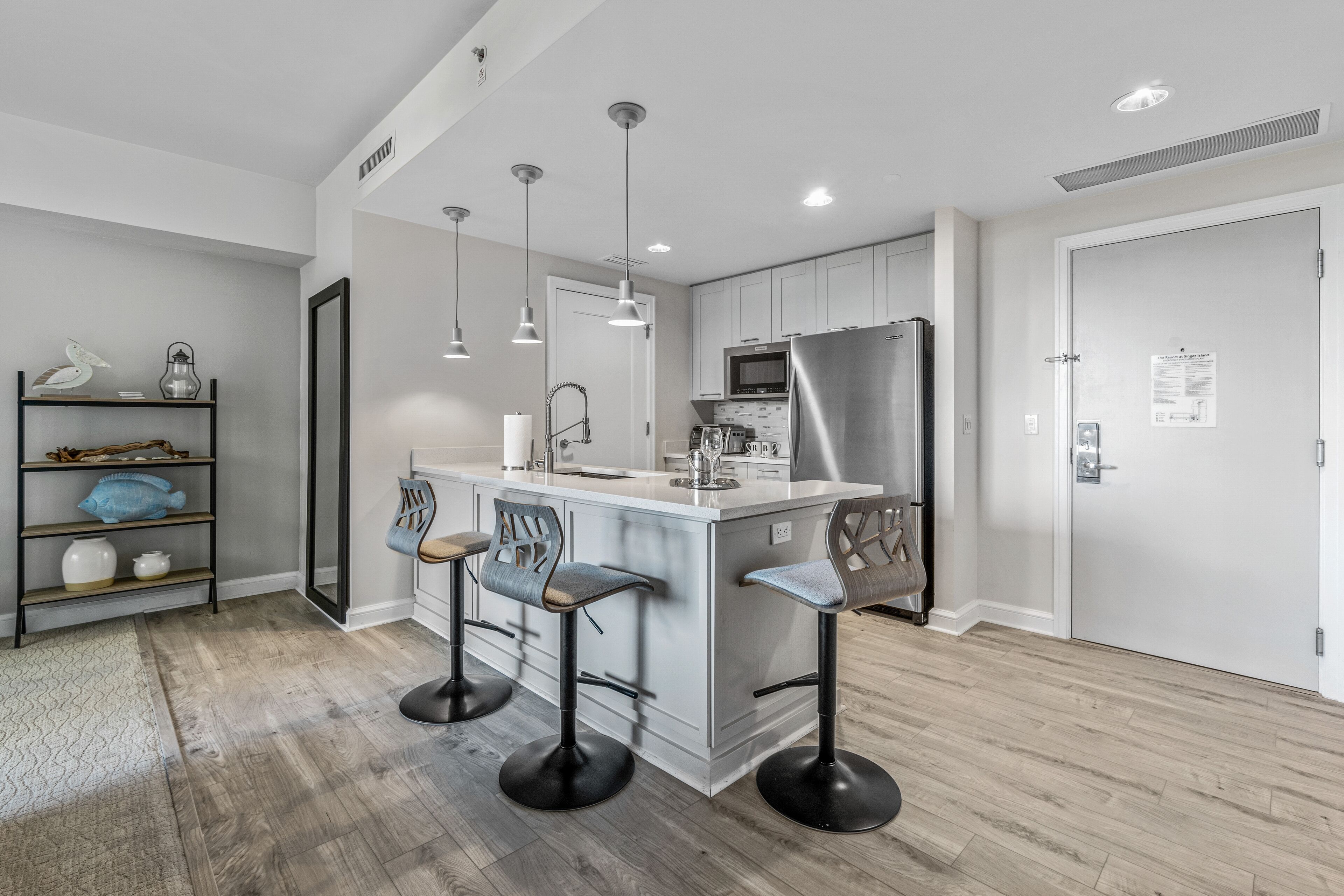 A modern kitchen with a central island, bar stools, and stainless steel appliances.