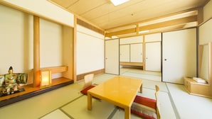 Een traditionele Japanse kamer met tatami vloerbedekking, een lage tafel, schuifdeuren en een klein standbeeld.