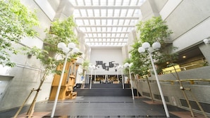 Een ruime atrium met een hoge plafond, een centrale trap en bomen aan beide kanten.