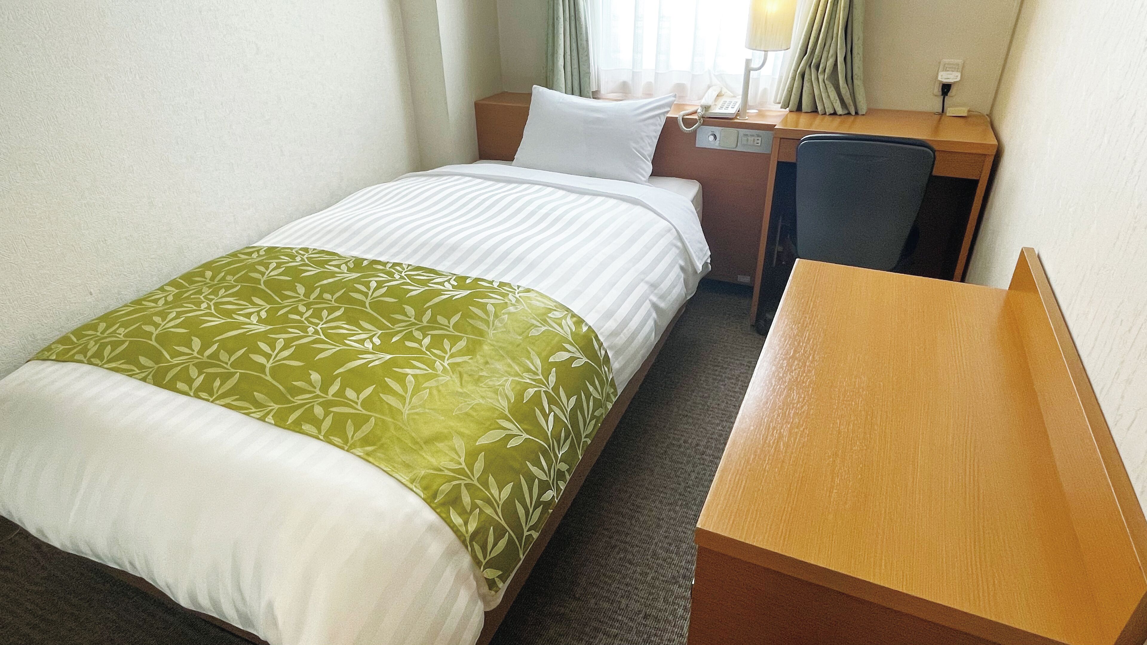 Una habitación de hotel con una cama, un escritorio, una silla, una lámpara y un teléfono.