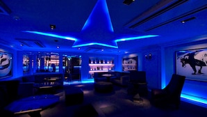 A modern lounge area with a star-shaped light fixture, comfortable seating, and a bar area visible through glass doors. - Rock Star Hotel (Osaka)