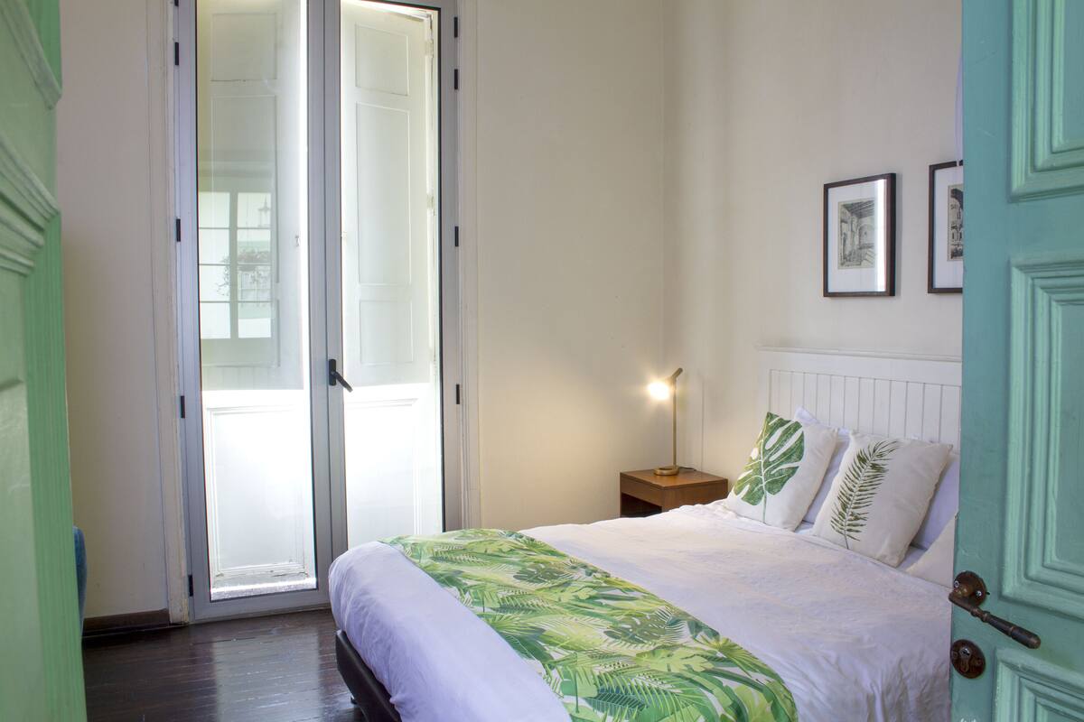 A bedroom with a bed, a nightstand, a lamp, and a door.