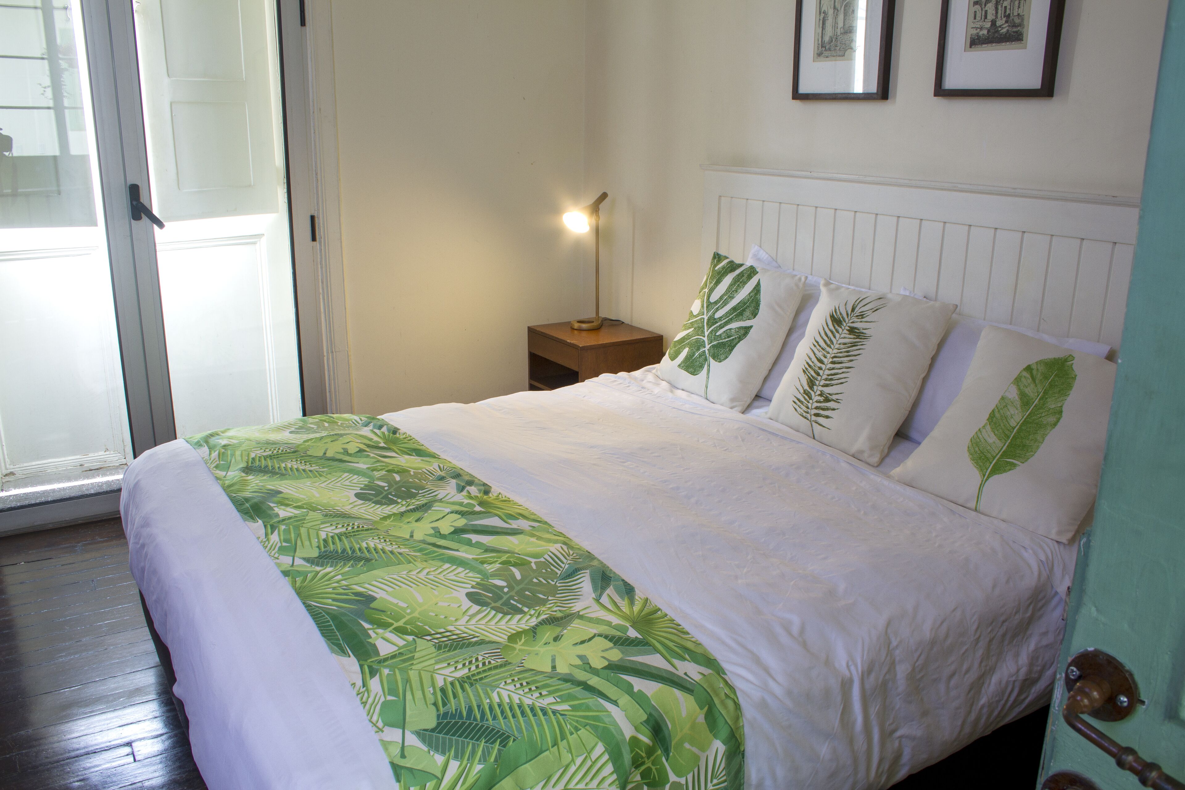 Une chambre à coucher avec un lit, une table de chevet, une lampe et une porte.