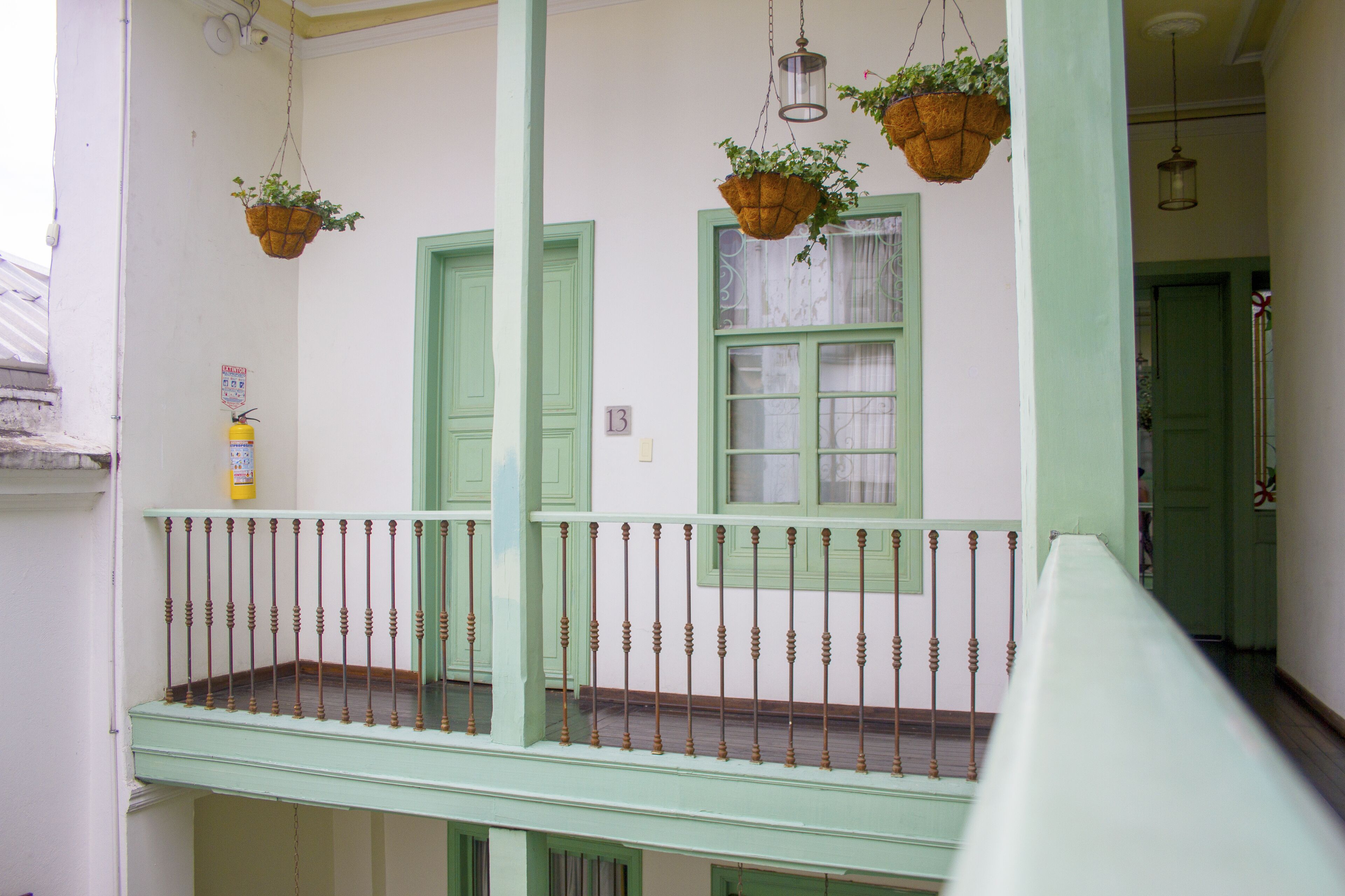 A balcony with a green railing and hanging flower baskets.