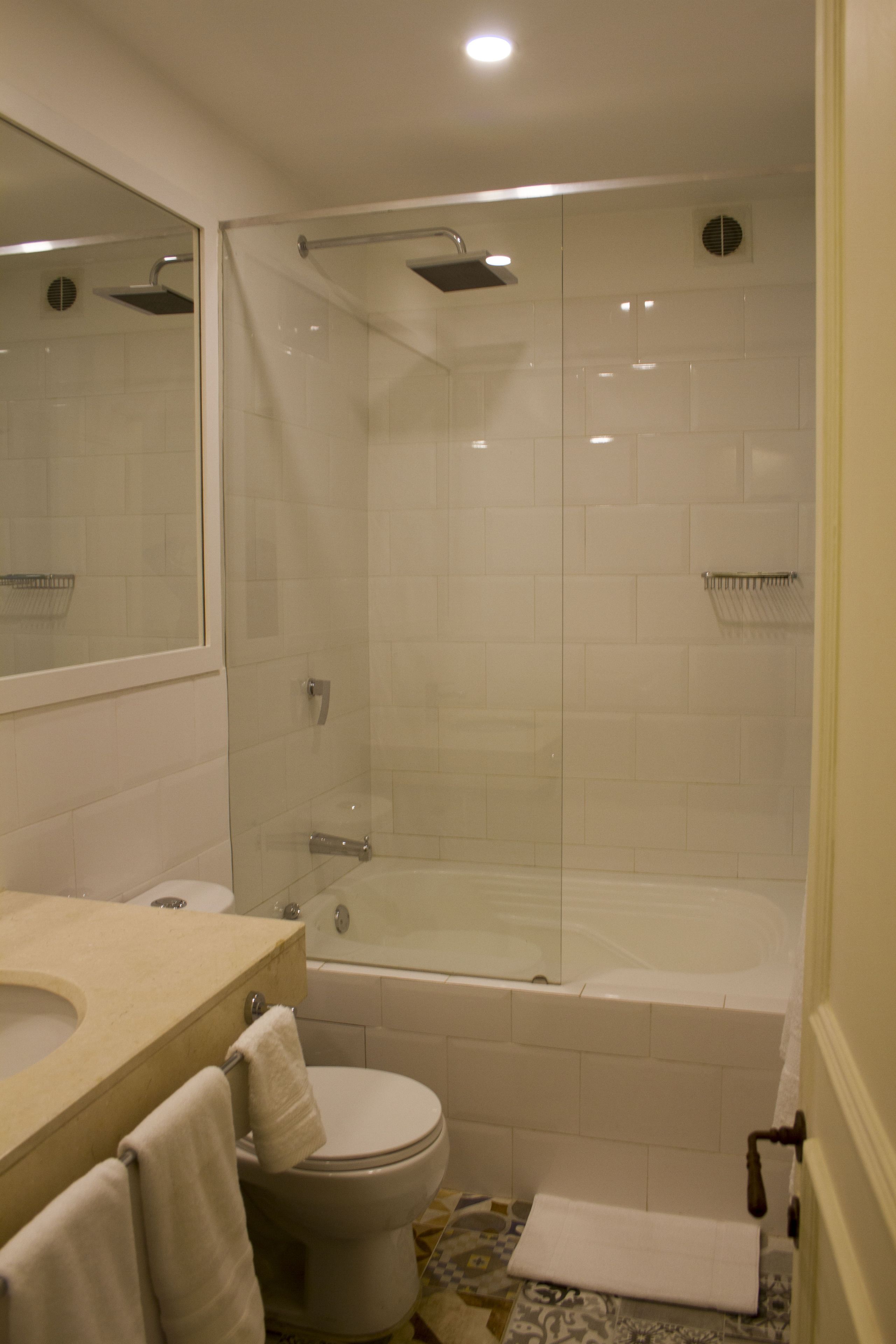 A bathroom with a glass-enclosed shower, a bathtub, a toilet, and a sink.