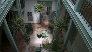 A courtyard with multiple seating areas, surrounded by potted plants and a tiled floor. - Hotel Casa De La Vega (Bogotá)