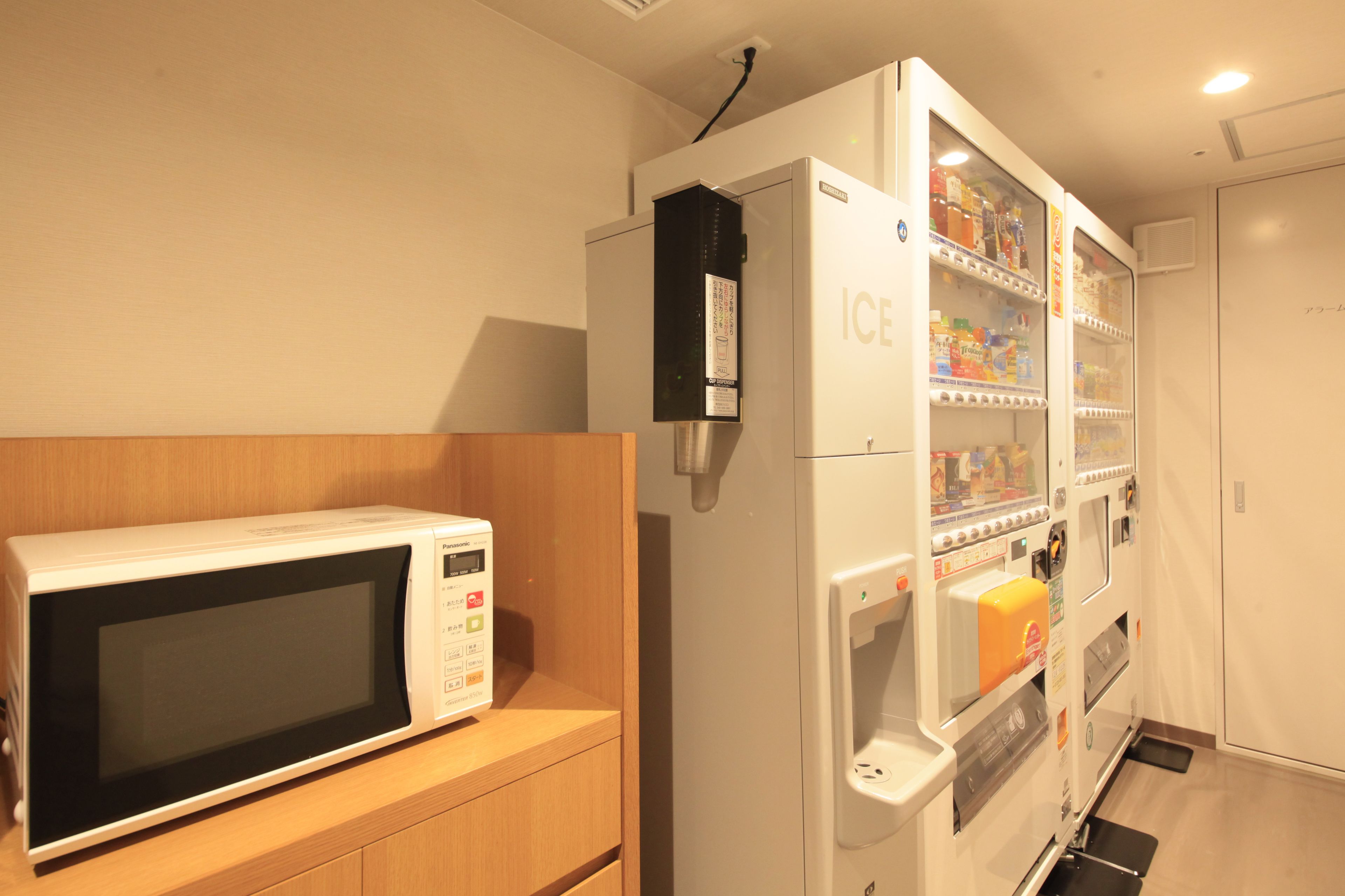 A kitchen area with a microwave and a refrigerator stocked with beverages.