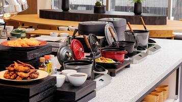 Disposição de buffet com diversos pratos, utensílios de cozinha e louças.