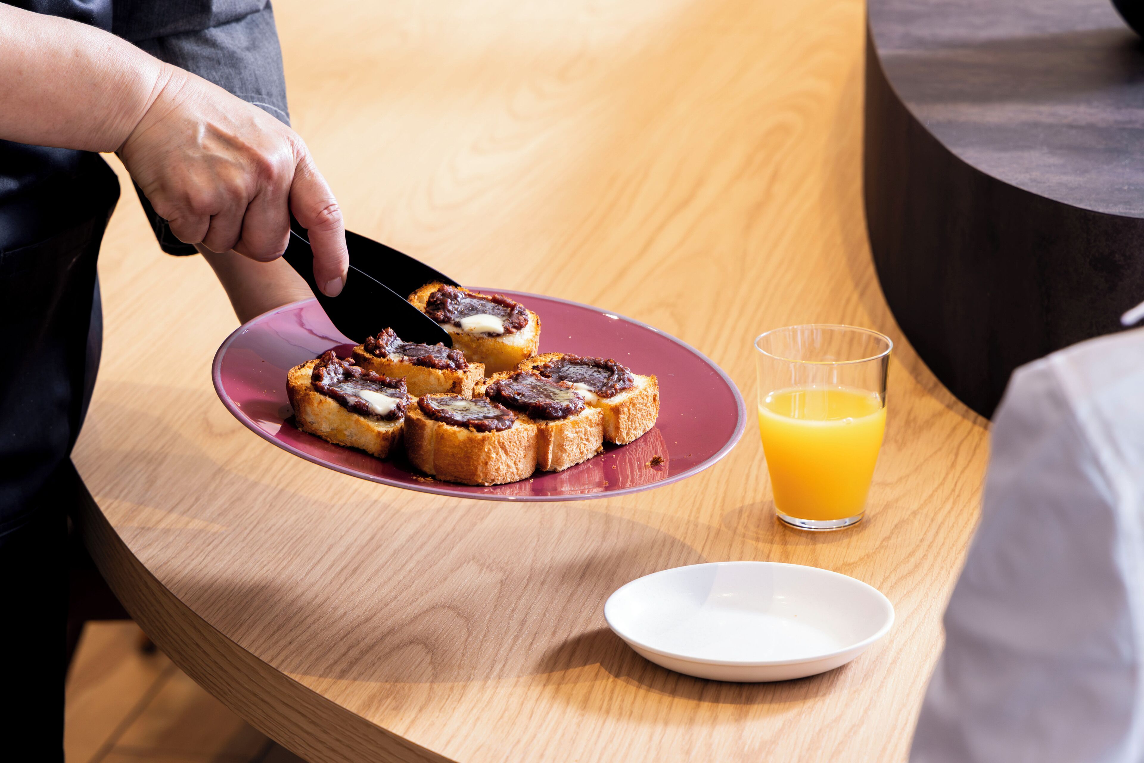 A breakfast setting with toast and a glass of orange juice on a wooden table.