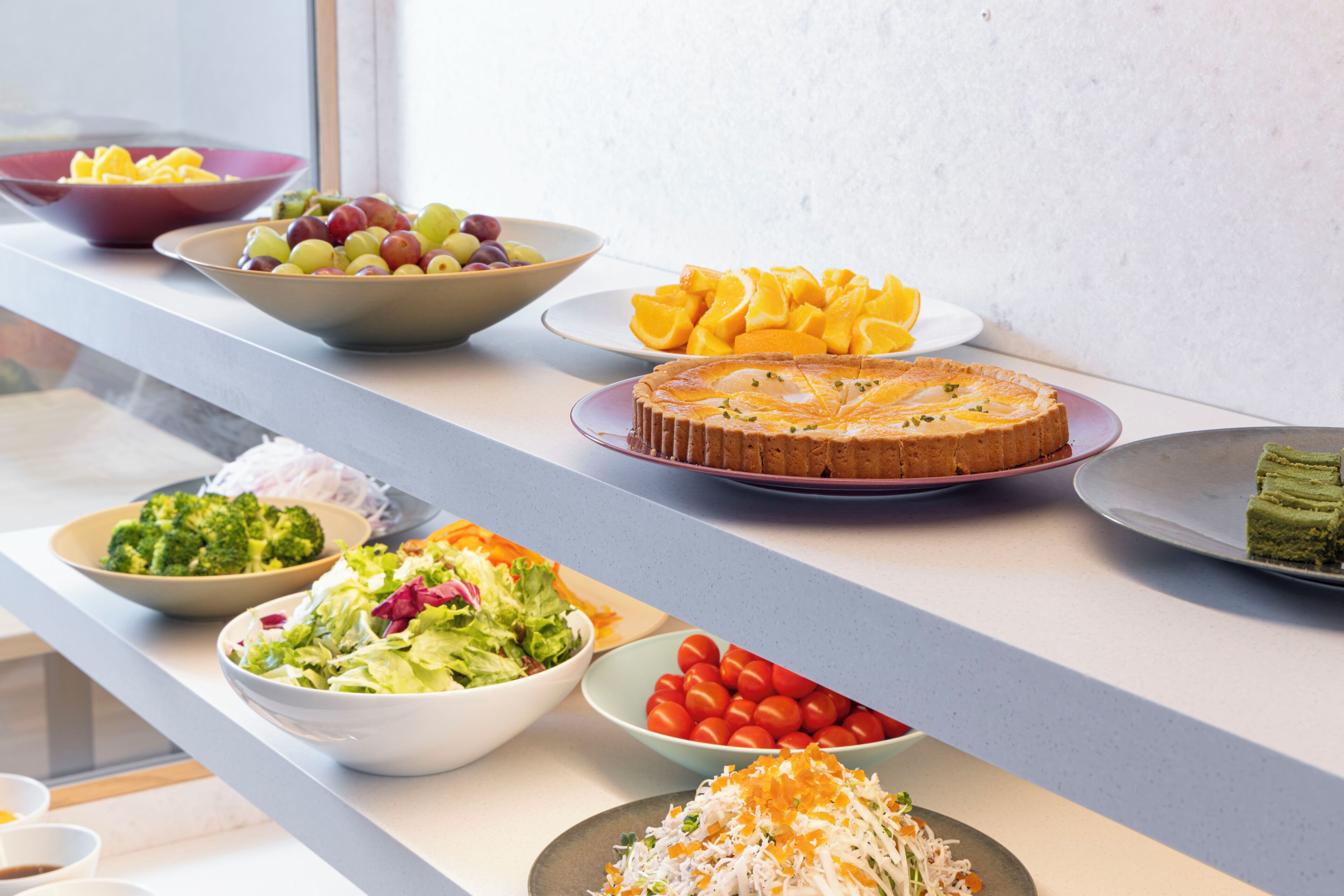 Buffet com diversos pratos, incluindo saladas, frutas e um bolo.