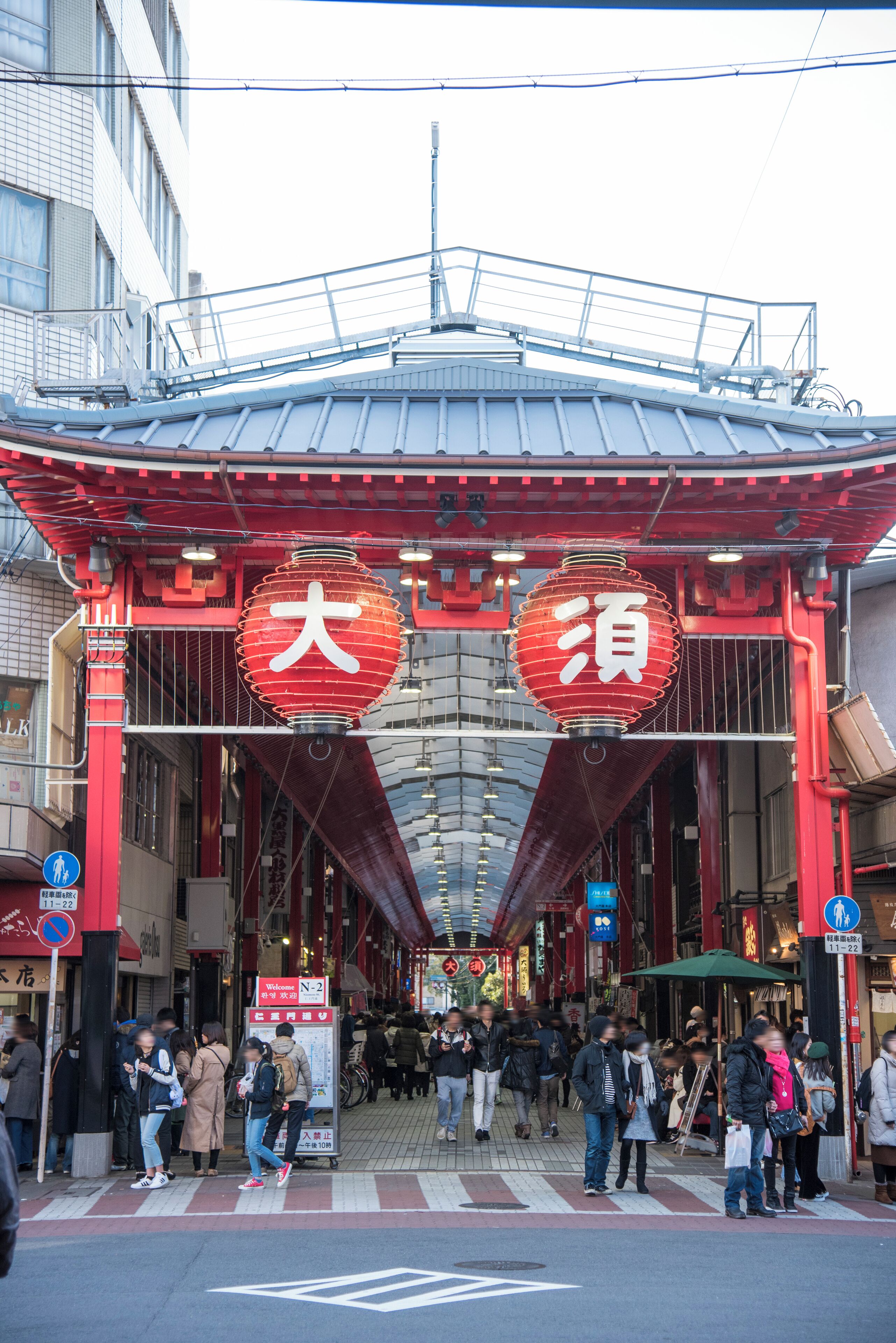 A traditional Japanese gate with red lanterns and a tiled roof.