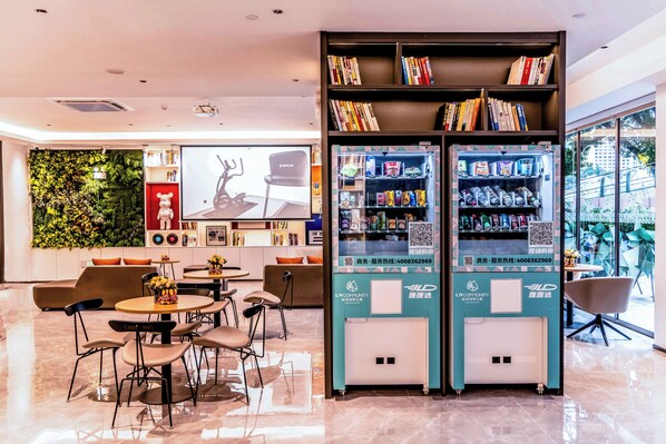 Un espacio interior moderno con una zona de estar, una estantería y una máquina expendedora.