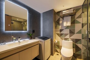 A modern bathroom with a large mirror, a built-in washing machine, a toilet, and a shower area. - LNCommunity (Guangzhou)