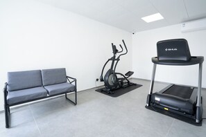 A fitness area with a grey sofa, an elliptical machine, and a treadmill. - LNCommunity (Guangzhou)