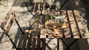 Een houten tafel met een kaasplank, olijven en wijnglazen.