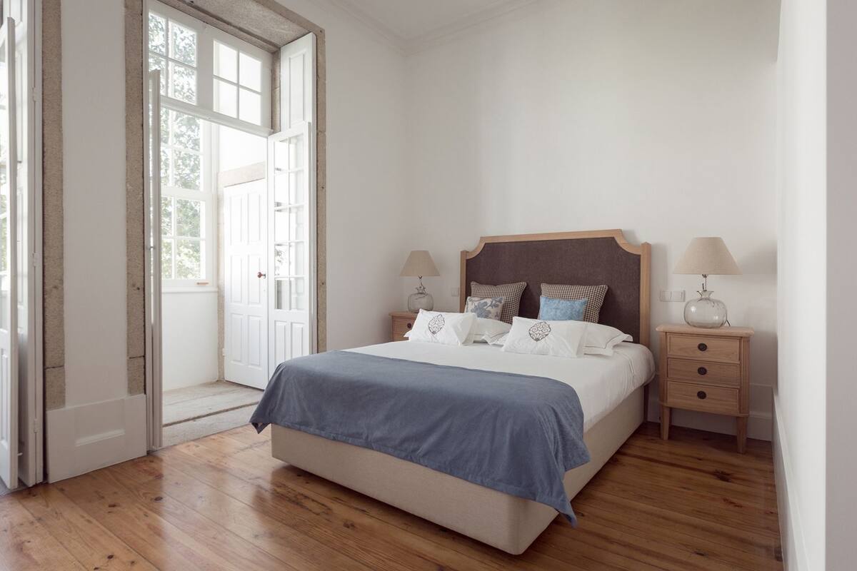 Une chambre à coucher avec un lit, des tables de chevet et une fenêtre donnant sur un beau paysage.