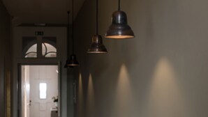 Een gang met hanglampen en een deur naar een kamer.