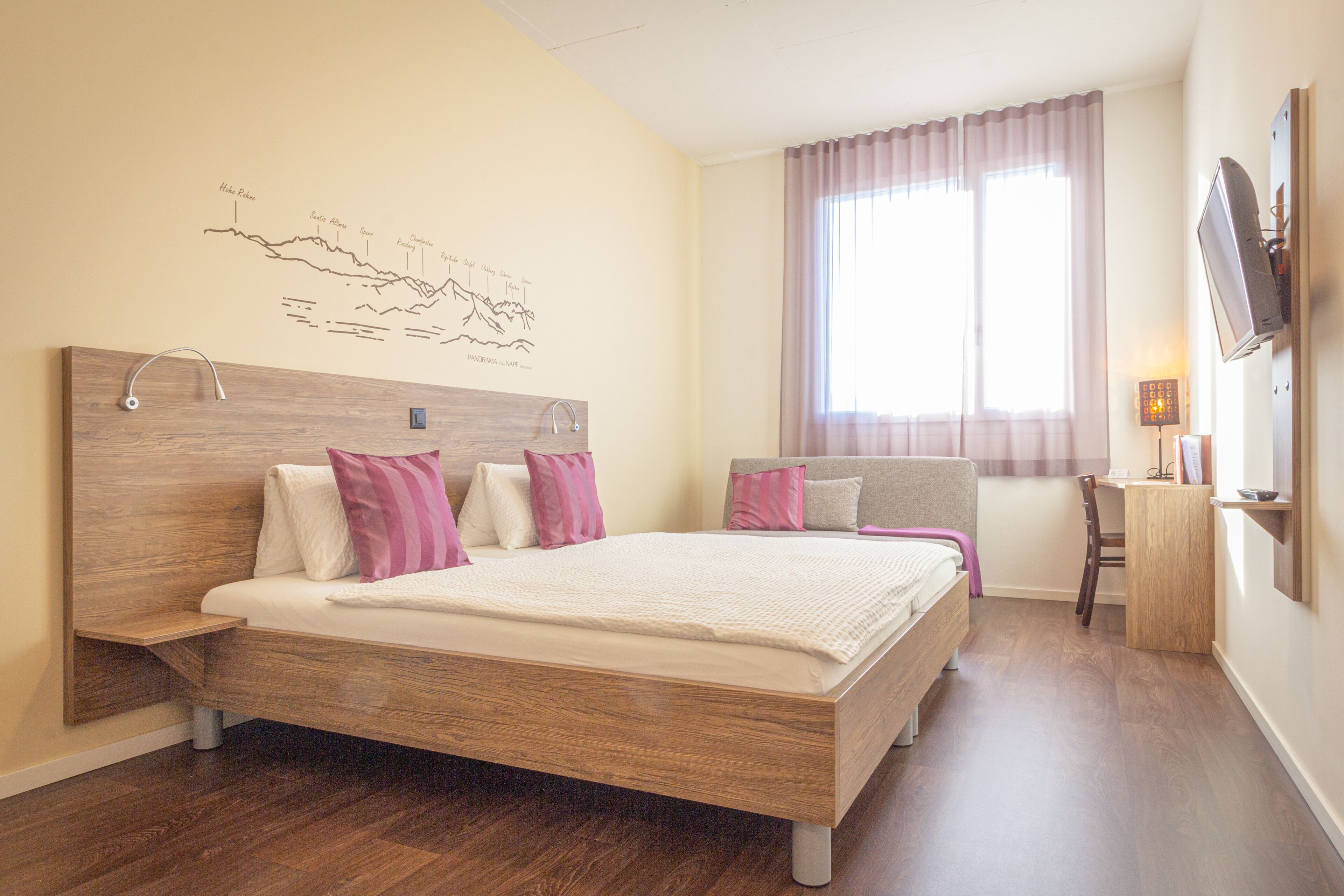 Un dormitorio con una cama grande, un escritorio y un televisor.