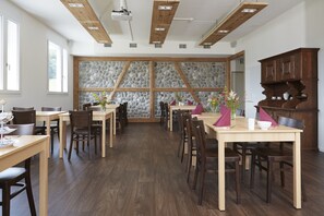 Un comedor amplio con mesas y sillas de madera, detalles en pared de piedra y techo de madera.