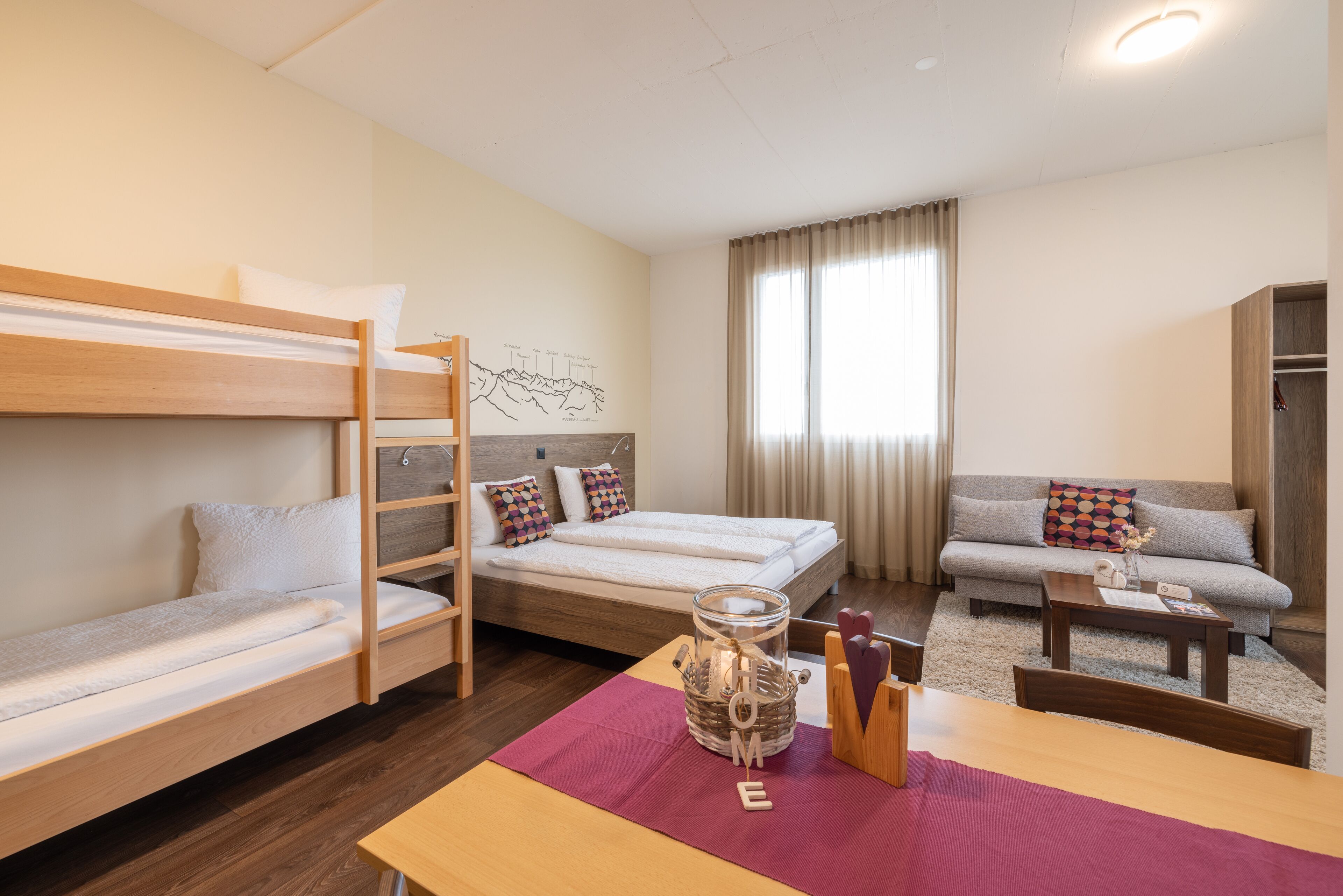 A dorm-style room with bunk beds, a sofa, a coffee table, and a decorative jar.