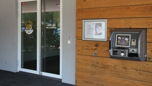 Entrada de un hotel con puerta de vidrio, panel de pared de madera y un quiosco de pago.