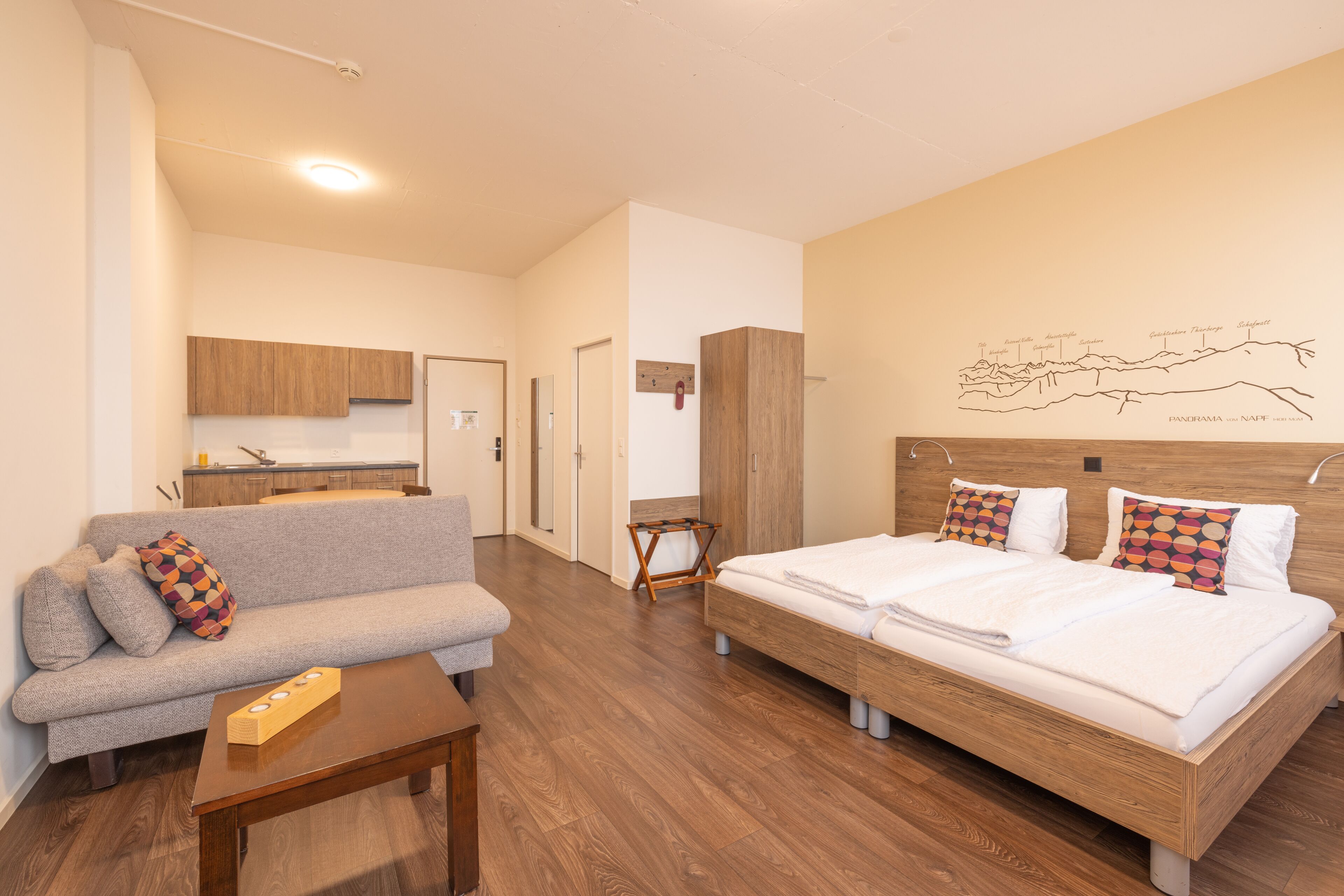 A modern hotel room with a sofa, a bed, a wooden coffee table, and a wall map.