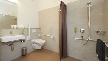 A modern bathroom with a sink, toilet, shower, and a mirror.