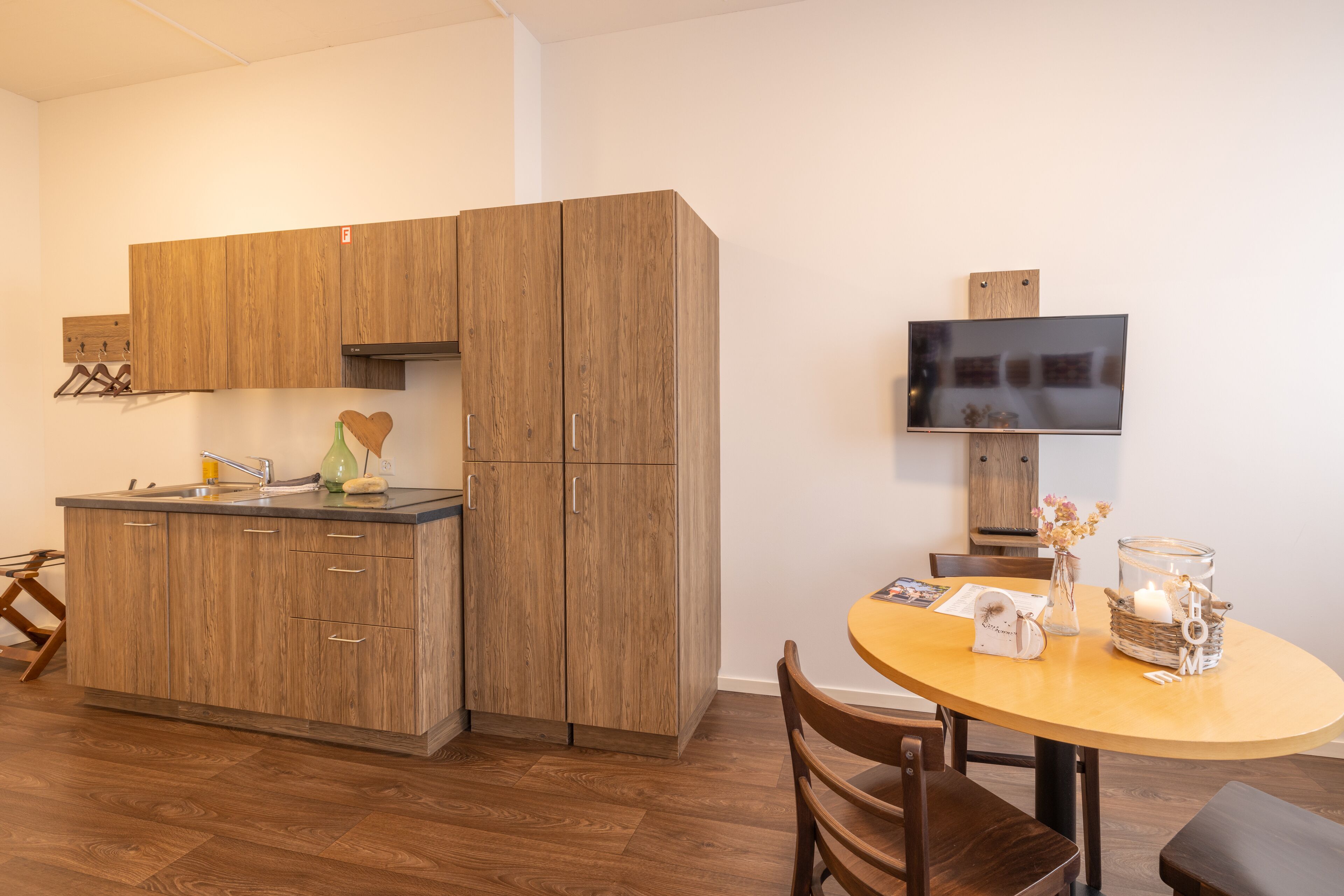 A modern kitchen with wooden cabinets, a built-in sink, and a dining area with a round table and chairs.