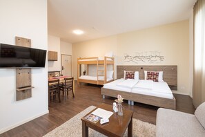 Una habitación de hotel moderna con una cama grande, un televisor montado en la pared, un escritorio con una silla y una litera.