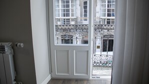 Una habitación con una puerta blanca que da a un balcón con barandilla decorada.
