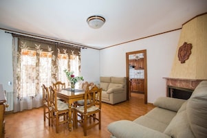 Una sala de estar con un sofá, una mesa de comedor con sillas y una chimenea.