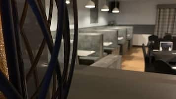 Un espacio de oficina moderno con cubículos, kitchenette e iluminación colgante.